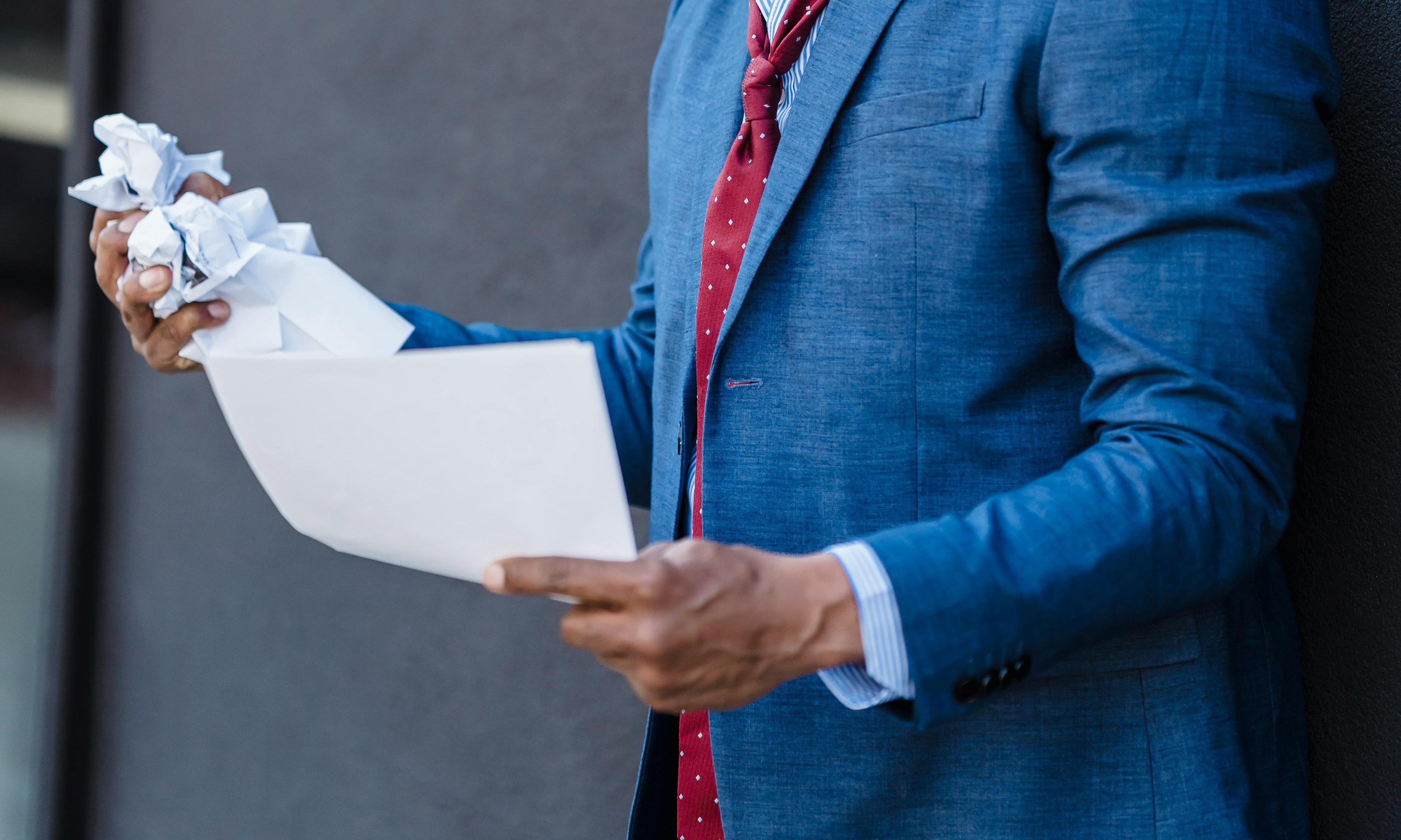 A man crumples up sheets of paper angrily | Source: Pexels