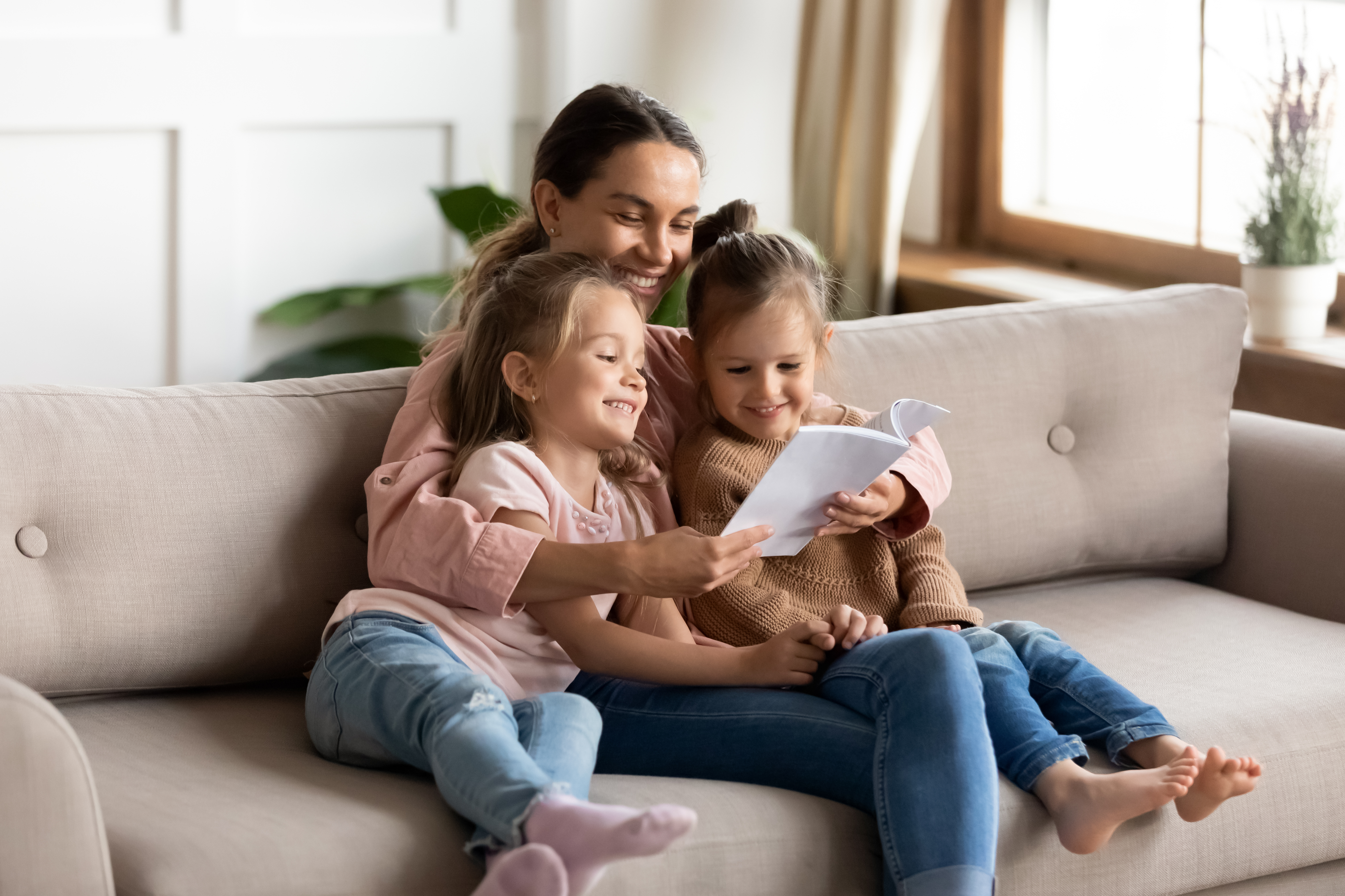 A woman reading a book to her daughters | Source: Shutterstock