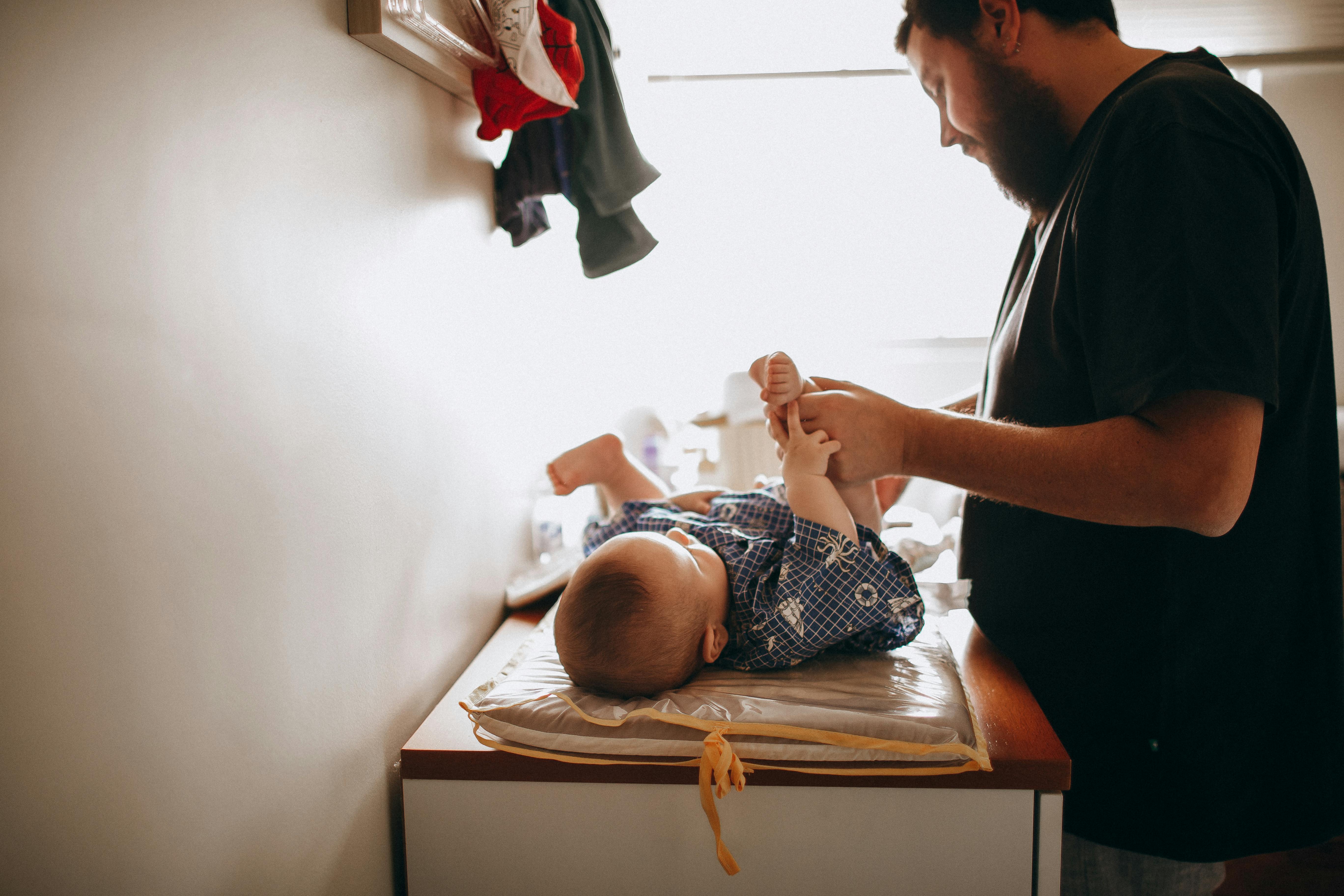 A dad changing a baby's diaper | Source: Pexels