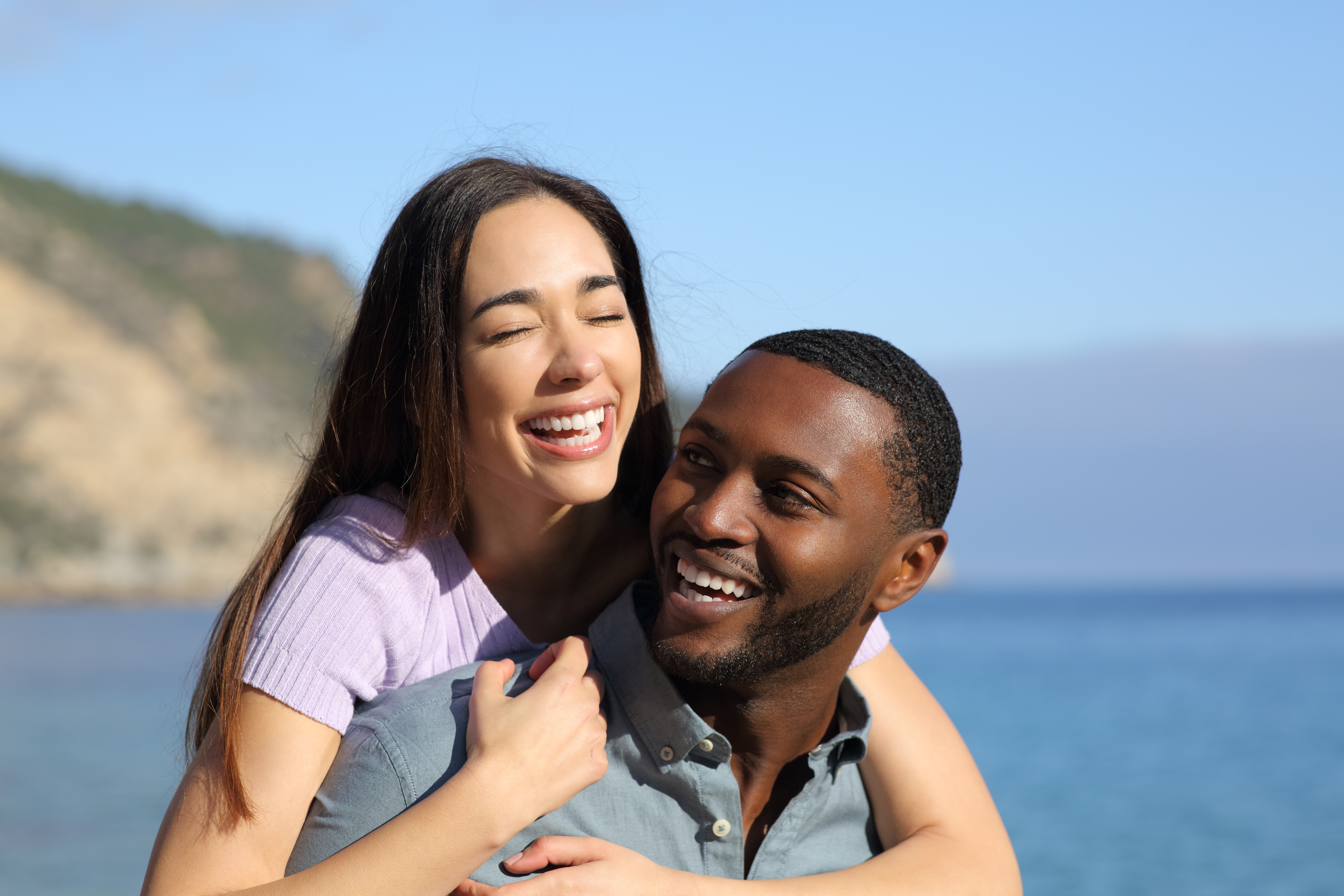 A happy interracial couple is pictured on the beach | Source: Shutterstock